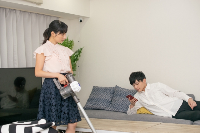掃除をする妻とだらける夫